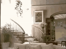 a living room with a couch , chairs , and stairs in a house .