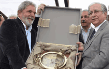 a man in a suit is holding a box with a clock inside