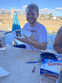 a man sitting at a table with a box of twizzlers