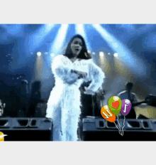 a woman singing on a stage with balloons that say j