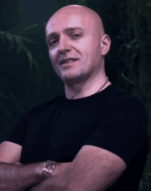 a bald man wearing a watch and a black shirt