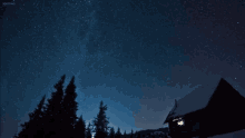 a starry night sky with a cabin in the foreground and a few trees in the background