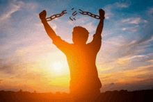 a silhouette of a man breaking a chain in front of a sunset