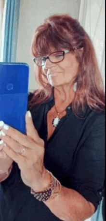 a woman wearing glasses looks at her phone