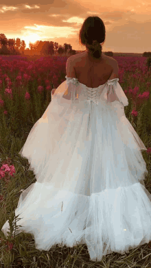 a woman in a white dress is standing in a field of pink flowers