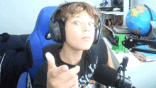 a young boy wearing headphones and a black shirt that says best in the world