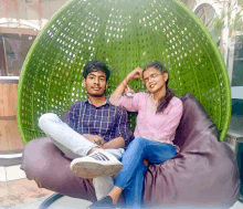 a man and a woman sit in a green wicker chair