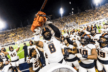 a football player with the number 8 on his jersey is holding a chainsaw