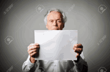 a man is holding a piece of paper in front of his face