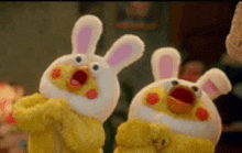 two stuffed animals dressed as rabbits are standing next to each other in a living room .