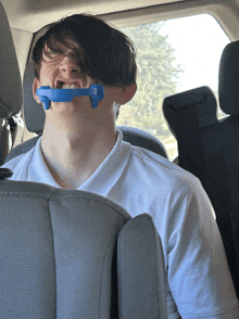 a young man in a car with a blue mouth guard on his mouth