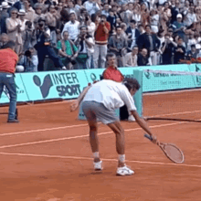 a man is holding a tennis racquet on a tennis court in front of a sign that says inter sport