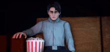 a man is sitting in a theater eating popcorn .