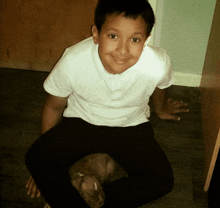 a young boy sits on the floor with a puppy