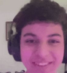 a young man wearing headphones is smiling for the camera .