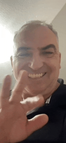 a man is smiling and giving a peace sign with his finger .