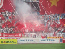 a crowd of people are watching a soccer game in a stadium with flares .