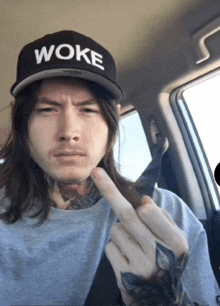 a man with long hair wearing a woke hat giving the middle finger