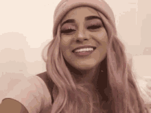 the woman is wearing a pink wig and a pink hat and smiling .