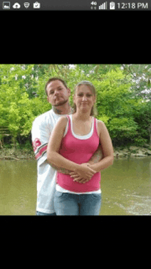 a man and woman are posing for a picture in front of a body of water