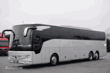 a white mercedes bus is parked in a parking lot next to a man truck