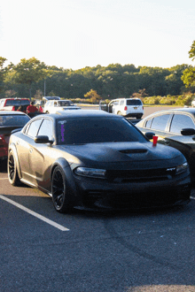 a black dodge charger is parked in a parking lot with a red cup on the hood