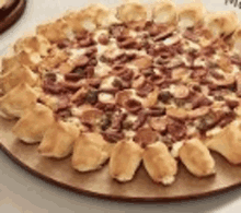 a pizza with bacon and cheese on a wooden cutting board .