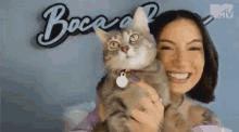 a woman is holding a cat in front of a sign that says boca .