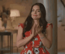 a woman in a red dress is clapping her hands and smiling .