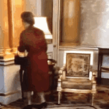 a woman in a red dress is standing in a room next to a chair .