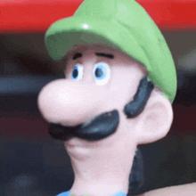 a close up of a mario figurine with a green hat and mustache .