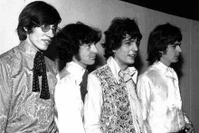 a black and white photo of the rolling stones standing next to each other .