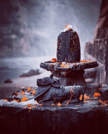 a statue of a man sitting on a rock next to a large stone statue