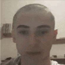 a man with a shaved head is looking at the camera .