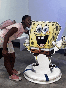 a girl standing next to a cardboard cutout of spongebob squarepants