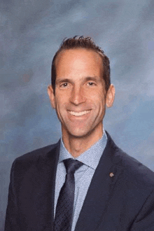 a man is wearing a suit and tie and smiling for the camera .