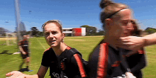 two female soccer players are standing on a field and one of them is holding the other 's face .