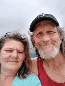 a man and a woman are posing for a picture and the man is wearing a black hat with a skull and crossbones on it