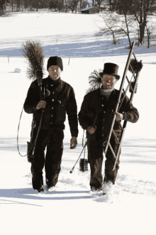 two chimney sweeps are walking through the snow carrying their tools