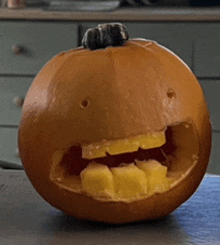 a pumpkin with a face carved into it has pineapple slices in its mouth