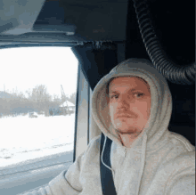 a man wearing a hoodie is driving a truck .