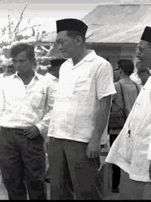 a black and white photo of a group of men standing next to each other in front of a building .