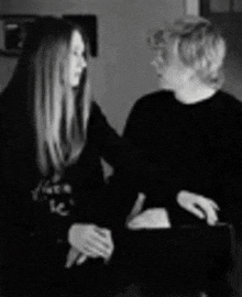 a man and a woman are sitting next to each other and talking in a black and white photo .