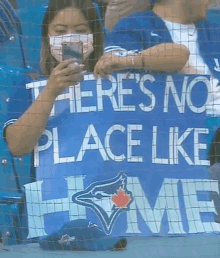 a blue jays fan holds up a sign that reads there 's no place like home