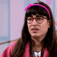 a woman wearing glasses and a pink headband has braces on her teeth