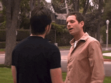 two men are standing next to each other in front of a house