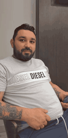 a man with a beard is wearing a white shirt that says diesel diesel