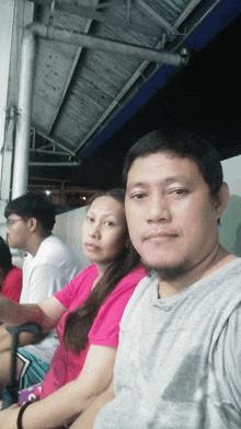 a man and a woman are posing for a picture with the man wearing a grey shirt