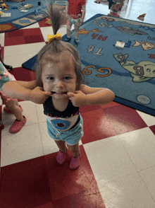 a little girl is making a funny face in front of a rug with the letters t and g on it