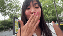 a woman covering her mouth with her hand in front of a yellow sign that says ' a ' on it